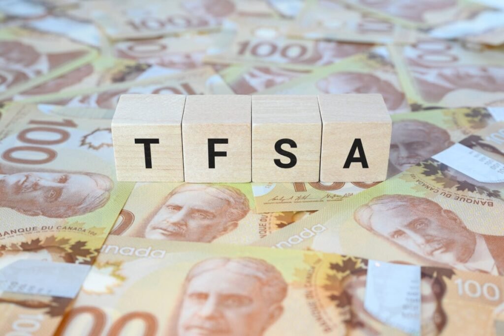 How to Use Your TFSA to Bring in $49 a Month Starting With Only $15,000 TFSA (Tax-Free Savings Account) on wooden blocks and Canadian one hundred dollar bills.